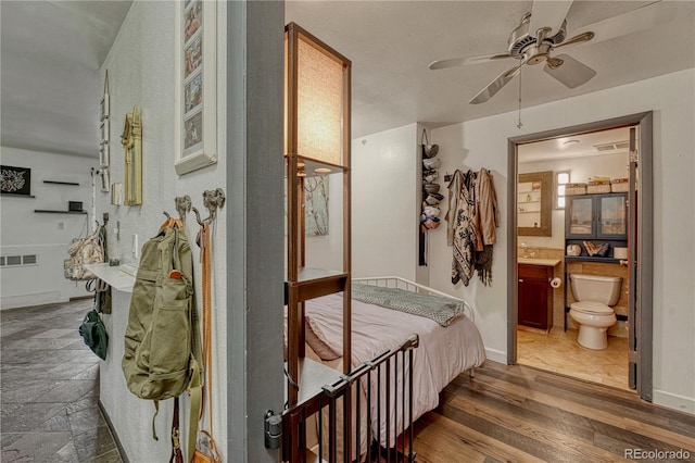 bedroom featuring baseboards, visible vents, wood finished floors, and ensuite bathroom