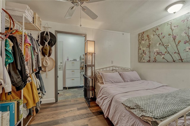 bedroom with a textured ceiling, a ceiling fan, and wood finished floors