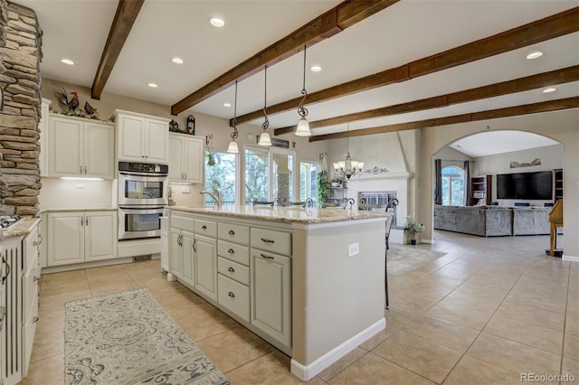 8320 Red Spring Valley Rd, Colorado Springs, CO 80919 - kitchen featuring double oven, open floor plan, light tile patterned floors, a kitchen island with sink, and arched walkways