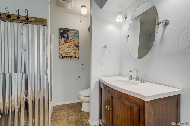 8320 Red Spring Valley Rd, Colorado Springs, CO 80919 - bathroom featuring toilet, vanity, an enclosed shower, stone finish floors, and baseboards