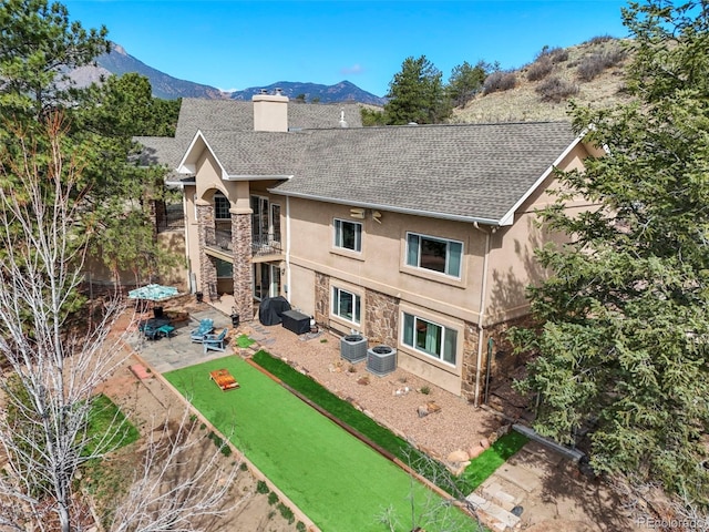 8320 Red Spring Valley Rd, Colorado Springs, CO 80919 - back of house featuring a balcony, stone siding, a chimney, roof with shingles, and a patio