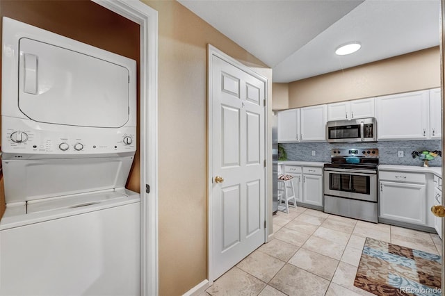 2428 W 82nd Pl Unit 1D, Westminster, CO 80031 - kitchen featuring appliances with stainless steel finishes, stacked washer / dryer, white cabinets, tasteful backsplash, and vaulted ceiling