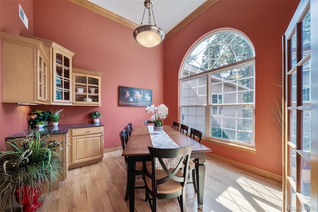 dining room with light hardwood / wood-style flooring and ornamental molding