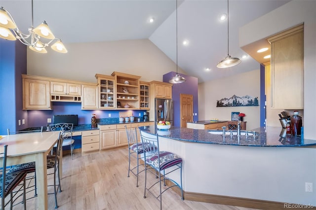 kitchen featuring stainless steel fridge with ice dispenser, built in desk, hanging light fixtures, and kitchen peninsula