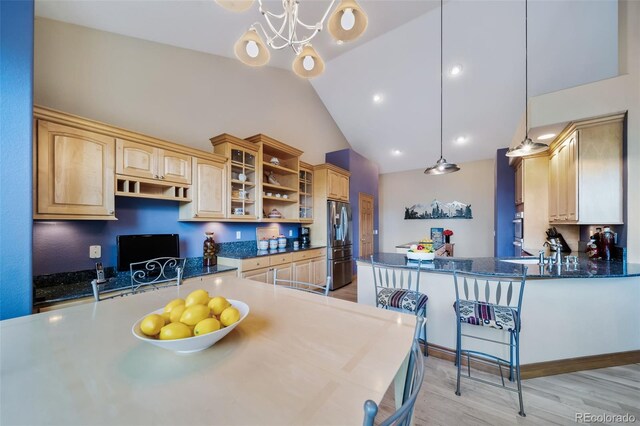 kitchen featuring light brown cabinets, pendant lighting, light wood-type flooring, lofted ceiling, and stainless steel appliances