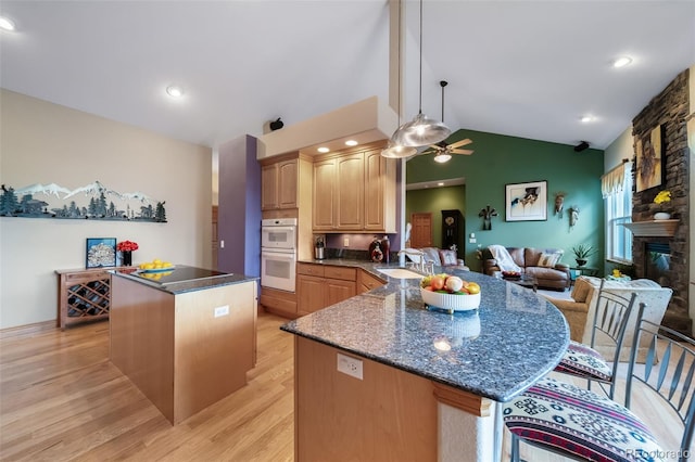 kitchen featuring kitchen peninsula, pendant lighting, light hardwood / wood-style flooring, double oven, and lofted ceiling