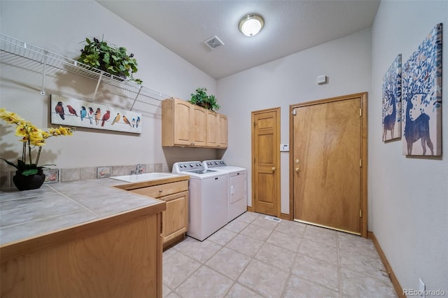 laundry room featuring sink, cabinets, a textured ceiling, and separate washer and dryer