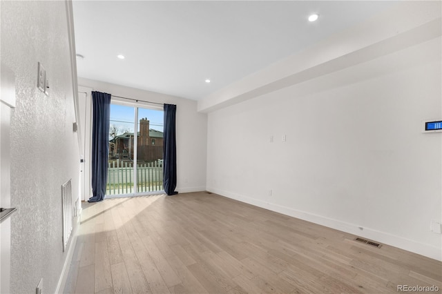 spare room featuring light wood finished floors, visible vents, recessed lighting, and baseboards