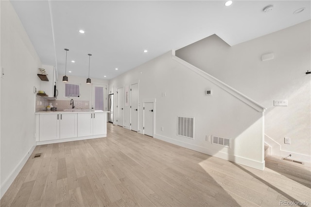 unfurnished living room featuring recessed lighting, visible vents, light wood-style floors, and stairs