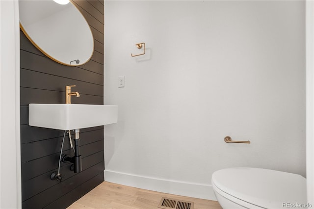 bathroom featuring visible vents, toilet, a sink, wood finished floors, and baseboards