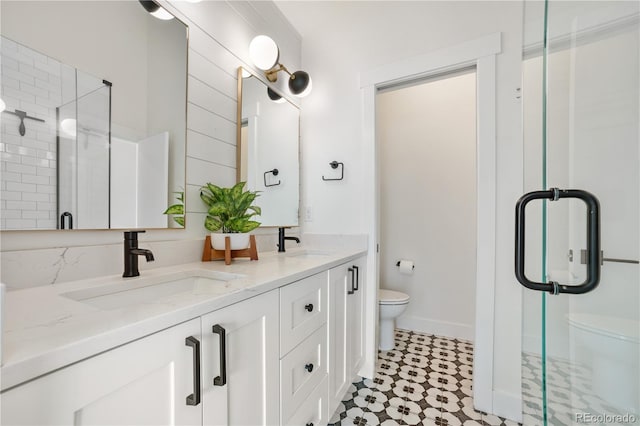 bathroom with a sink, toilet, a stall shower, and double vanity