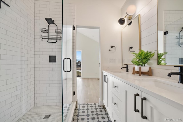 bathroom featuring a sink, lofted ceiling, a stall shower, and double vanity