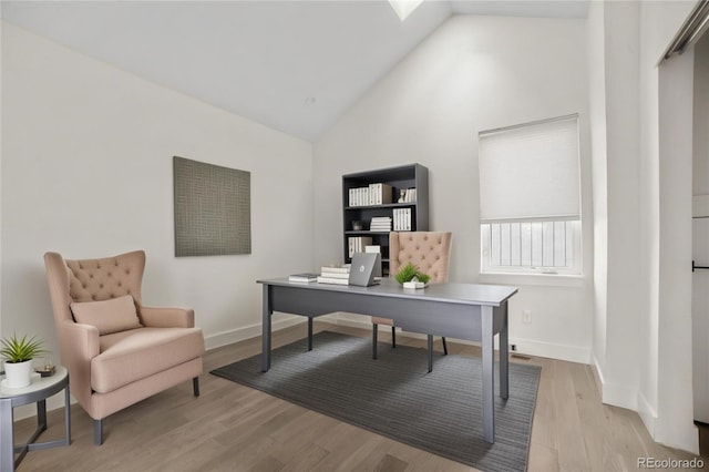 office area featuring baseboards, light wood-type flooring, and high vaulted ceiling