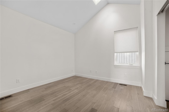 empty room with visible vents, light wood-type flooring, and lofted ceiling