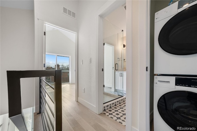 washroom featuring wood finished floors, visible vents, baseboards, laundry area, and stacked washer / dryer