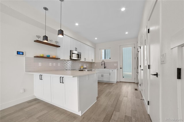 1907 W Elk Pl, Denver, CO 80211 - kitchen with stainless steel microwave, a peninsula, tasteful backsplash, light wood-style floors, and white cabinetry