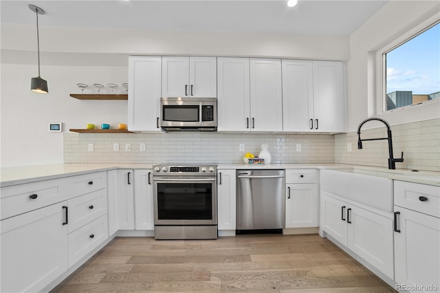 1907 W Elk Pl, Denver, CO 80211 - kitchen with appliances with stainless steel finishes, light wood-style flooring, light countertops, white cabinetry, and open shelves