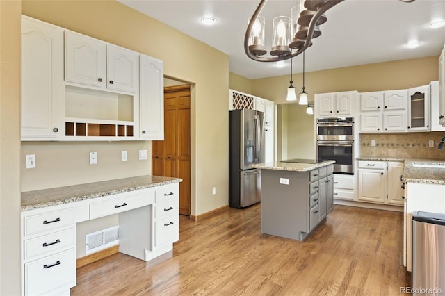 8286 W 108th Pl, Westminster, CO 80021 - kitchen featuring appliances with stainless steel finishes, white cabinets, light stone counters, decorative backsplash, and a kitchen island