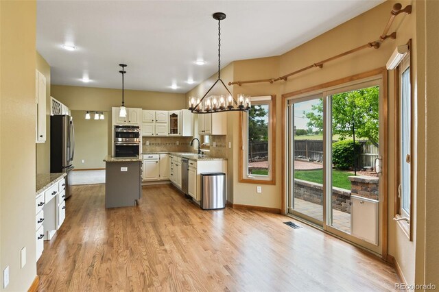 8286 W 108th Pl, Westminster, CO 80021 - kitchen with stainless steel appliances, a kitchen island, decorative backsplash, and light wood-style flooring