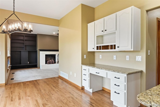 8286 W 108th Pl, Westminster, CO 80021 - kitchen with light wood-style floors, white cabinets, built in desk, light stone countertops, and a chandelier
