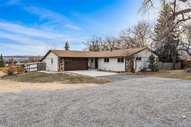 ranch-style house featuring driveway, an attached garage, roof with shingles, and fence