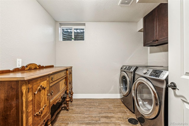 clothes washing area with wood finished floors, cabinet space, washer and clothes dryer, visible vents, and baseboards