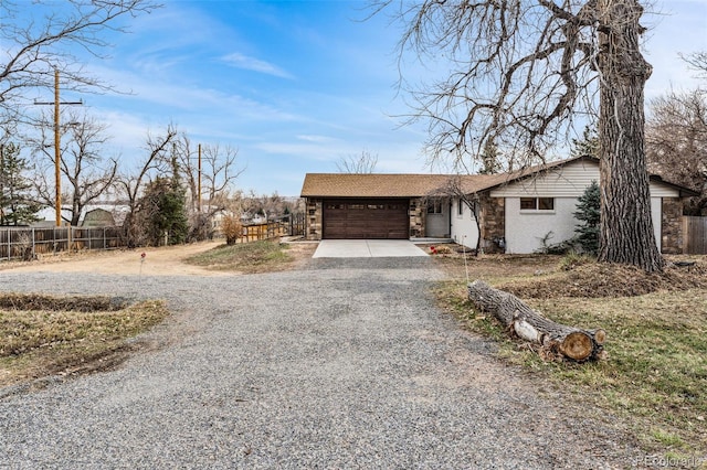 view of front facade with stone siding, fence, driveway, and an attached garage