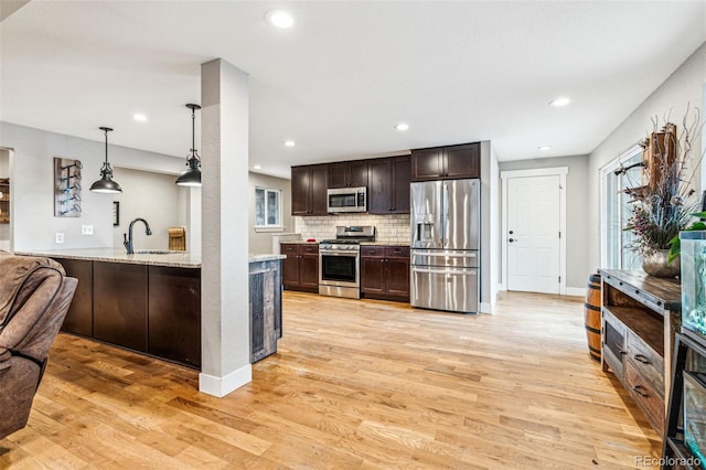 14290 W 54th Ave, Arvada, CO 80002 - kitchen with stainless steel appliances, dark brown cabinetry, light wood-style floors, tasteful backsplash, and hanging light fixtures