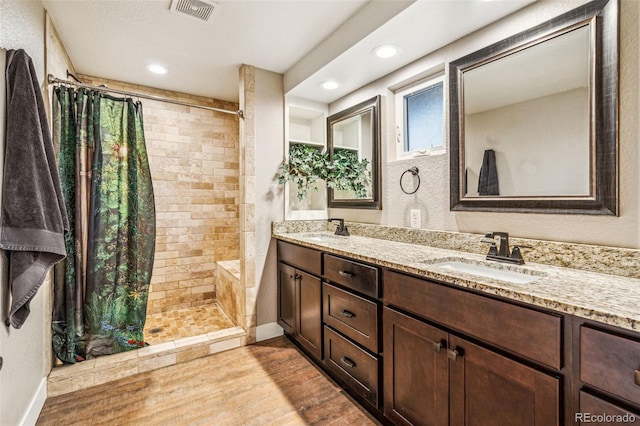 14290 W 54th Ave, Arvada, CO 80002 - bathroom featuring tiled shower, wood finished floors, double vanity, recessed lighting, and baseboards