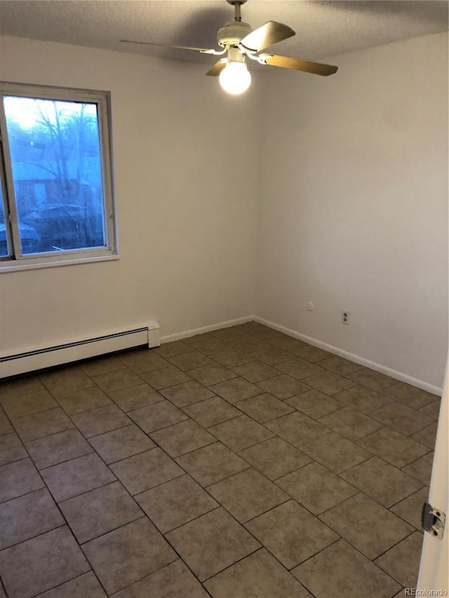 empty room featuring ceiling fan, dark tile floors, baseboard heating, and a textured ceiling