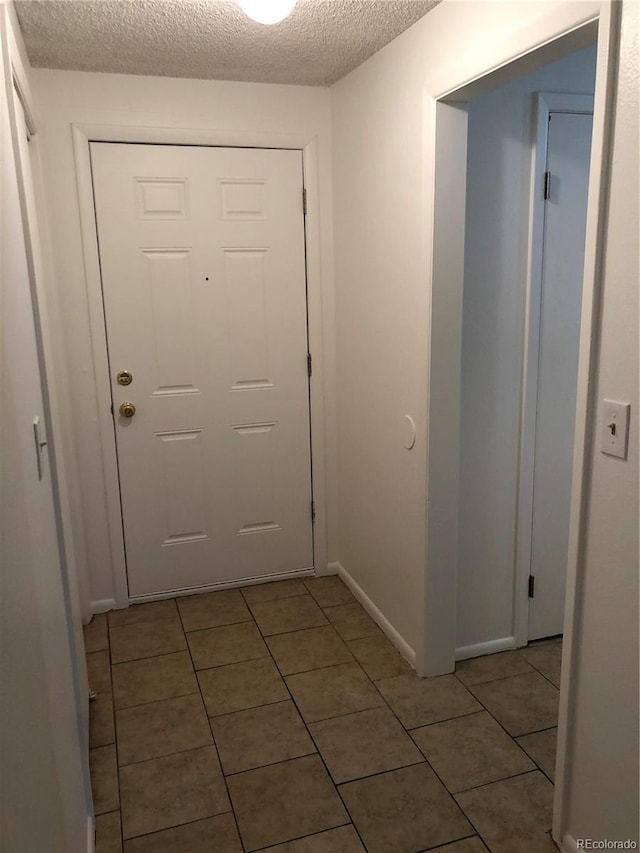 entryway featuring light tile flooring and a textured ceiling