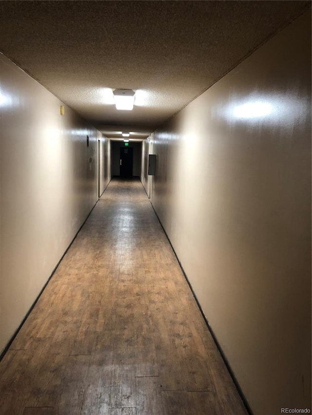 corridor with hardwood / wood-style flooring and a textured ceiling