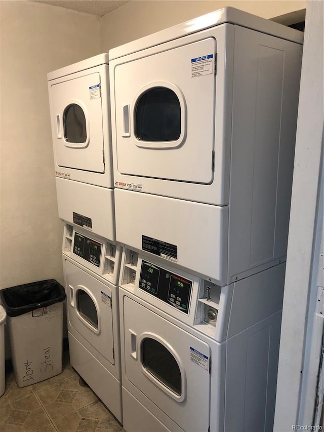 washroom featuring dark tile floors, washing machine and clothes dryer, and stacked washer / drying machine