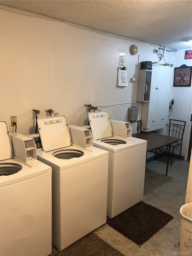 clothes washing area with tile flooring, hookup for a washing machine, separate washer and dryer, and a textured ceiling