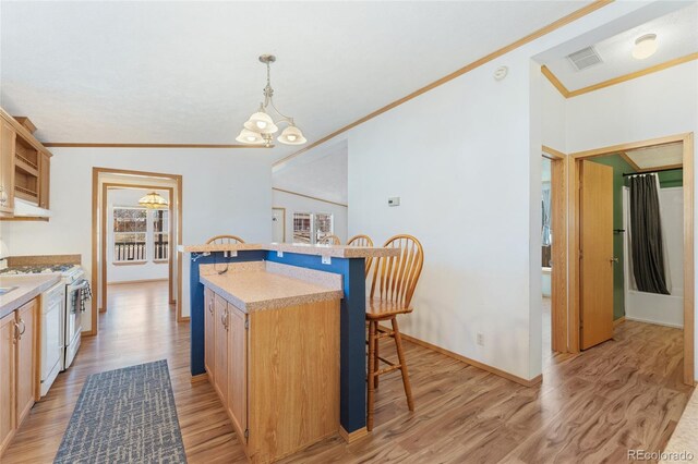 2019 S Fox St, Denver, CO 80223 - kitchen with white gas stove, ornamental molding, a kitchen bar, light wood-style floors, and a kitchen island with sink