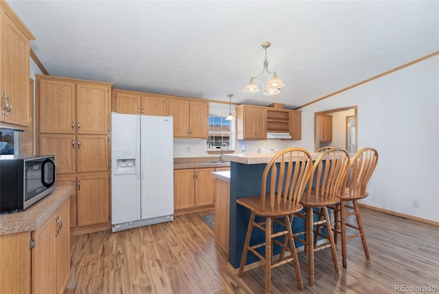 2019 S Fox St, Denver, CO 80223 - kitchen featuring white fridge with ice dispenser, stainless steel microwave, light wood-type flooring, light countertops, and a breakfast bar area