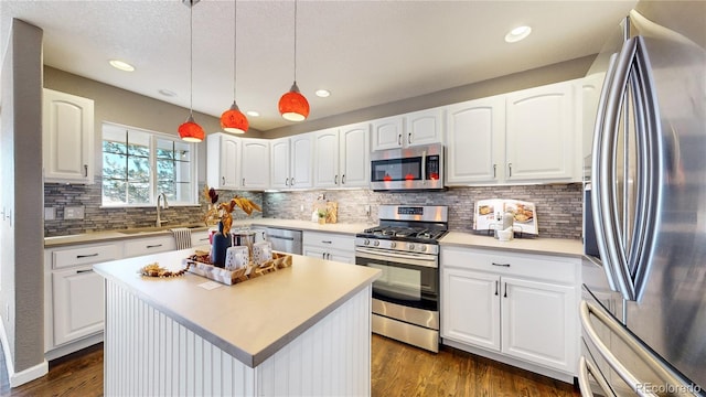 kitchen with a center island, hanging light fixtures, sink, appliances with stainless steel finishes, and white cabinetry