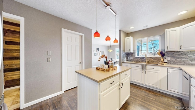 kitchen featuring white cabinets, decorative backsplash, hanging light fixtures, and sink