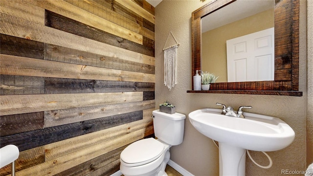 bathroom featuring wood walls and toilet