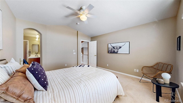 bedroom featuring vaulted ceiling, light colored carpet, ensuite bath, and ceiling fan