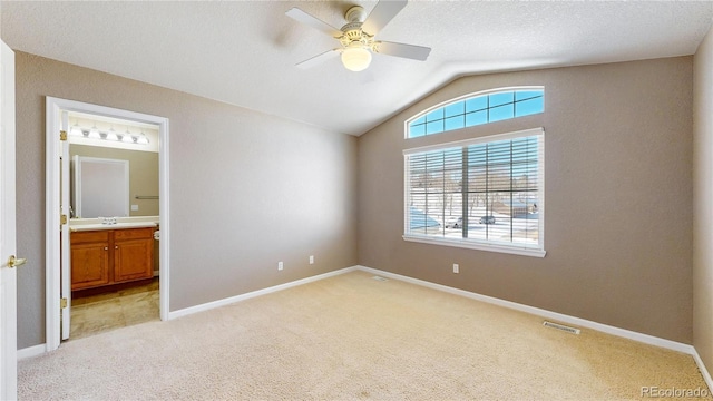 unfurnished bedroom with ensuite bath, ceiling fan, light colored carpet, and vaulted ceiling