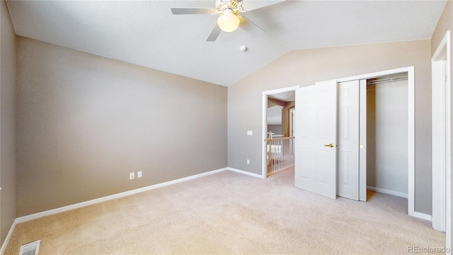 unfurnished bedroom featuring light carpet, a closet, vaulted ceiling, and ceiling fan