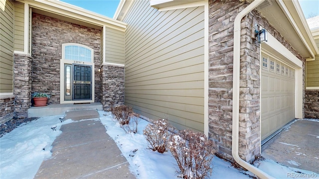 snow covered property entrance featuring a garage