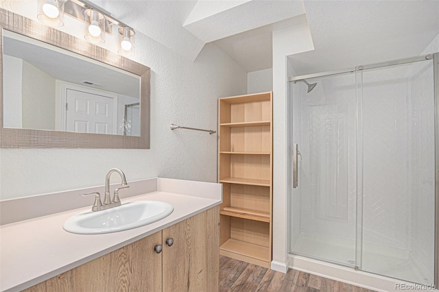 23841 E Alabama Dr, Aurora, CO 80018 - full bathroom with a shower stall, wood finished floors, a textured wall, and vanity
