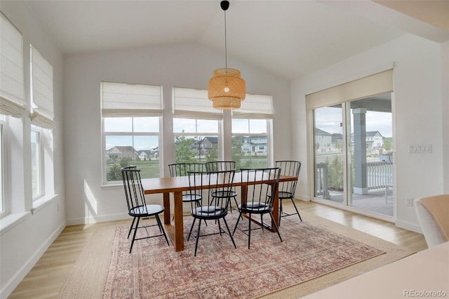 dining area with light wood-style floors, lofted ceiling, and baseboards