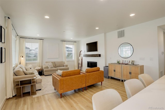 living room featuring light wood finished floors, a glass covered fireplace, and recessed lighting