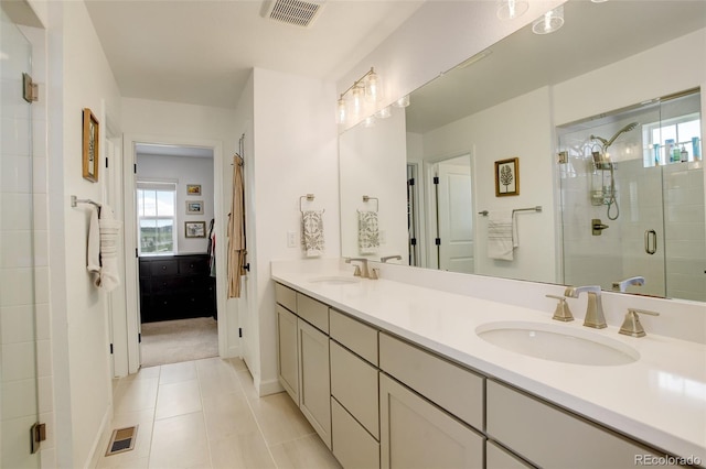 bathroom with healthy amount of natural light, a stall shower, double vanity, and tile patterned flooring