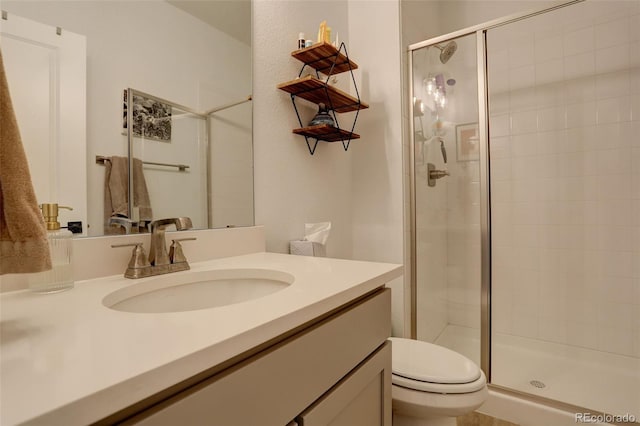 bathroom with a stall shower, toilet, and vanity