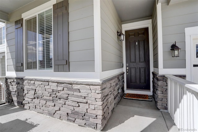 view of exterior entry featuring covered porch and stone siding