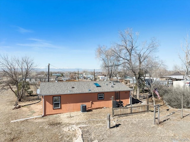 back of property featuring a shingled roof and central AC unit